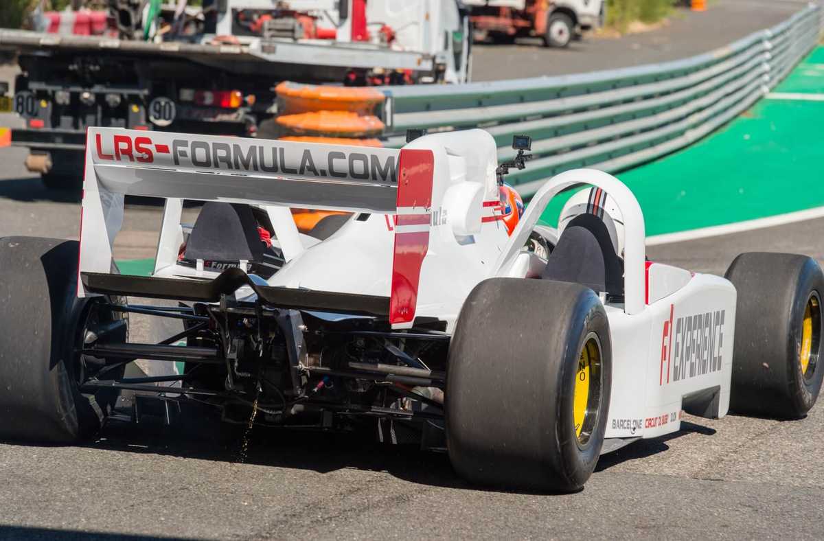 Ferrari race car crossing the finish line at Circuit de Barcelona-Catalunya with heat shimmer and crowd in the background