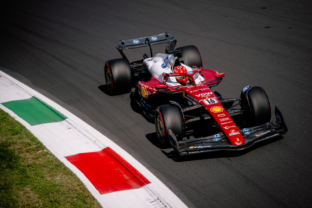 Front three-quarter shot of a Ferrari F1 car rotating into a corner with visible front-end bite