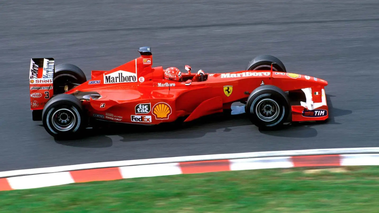 Mick Schumacher driving the Haas F1 car during a Grand Prix, wheels kicking up spray on a wet track