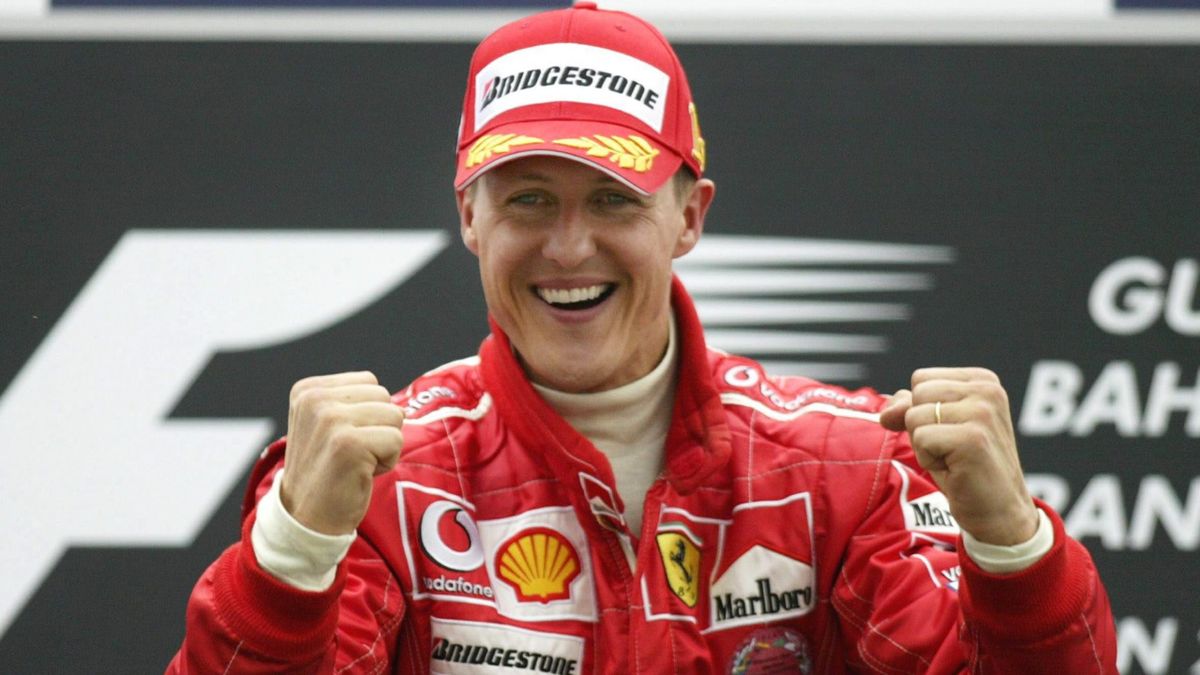 Michael Schumacher standing next to a red Ferrari F1 car on the grid