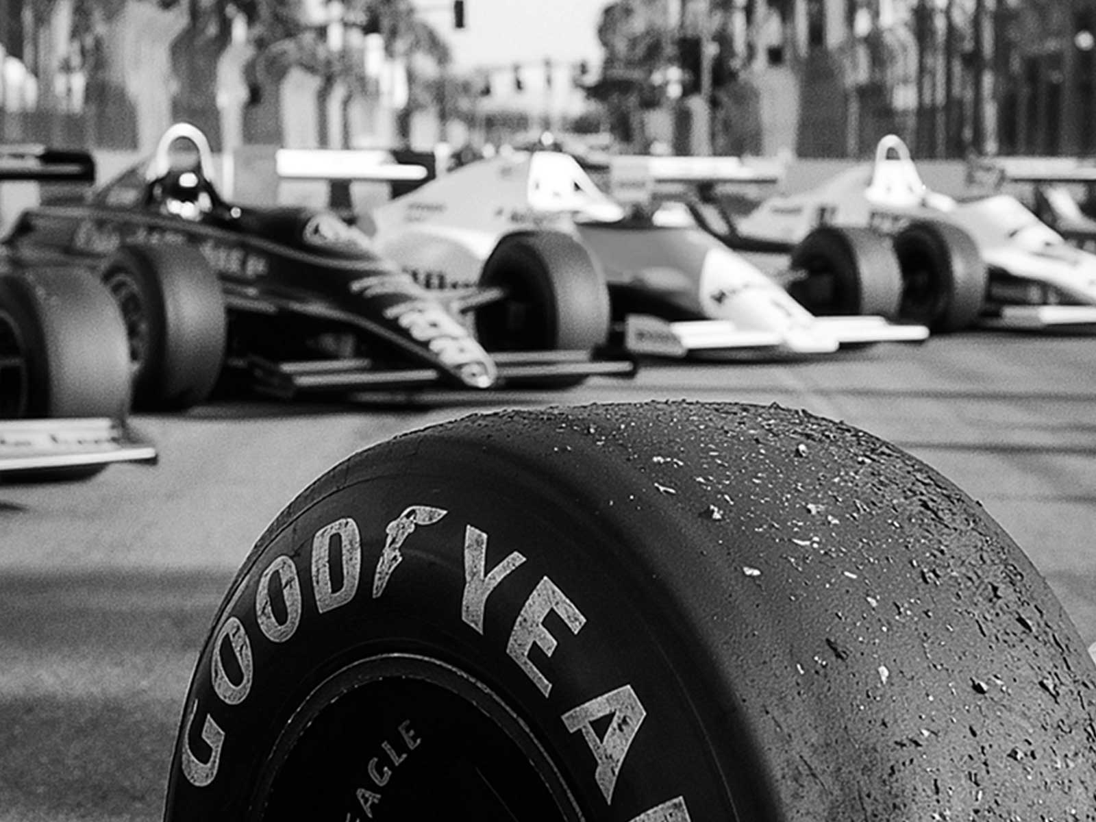 Reflections of palm trees and neon signage on the curved surfaces of a Formula 1 car body in Miami lighting