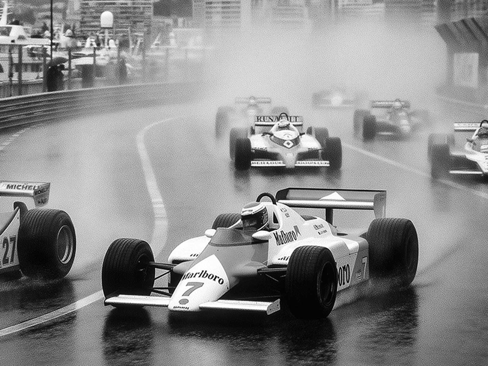 Hero poster with dramatic stormy sky above a rain-lashed starting grid, compositional balance between sky, track, and…